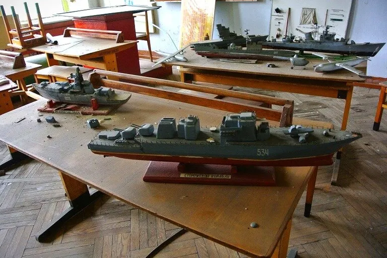 a room filled with lots of wooden desks covered in model ships