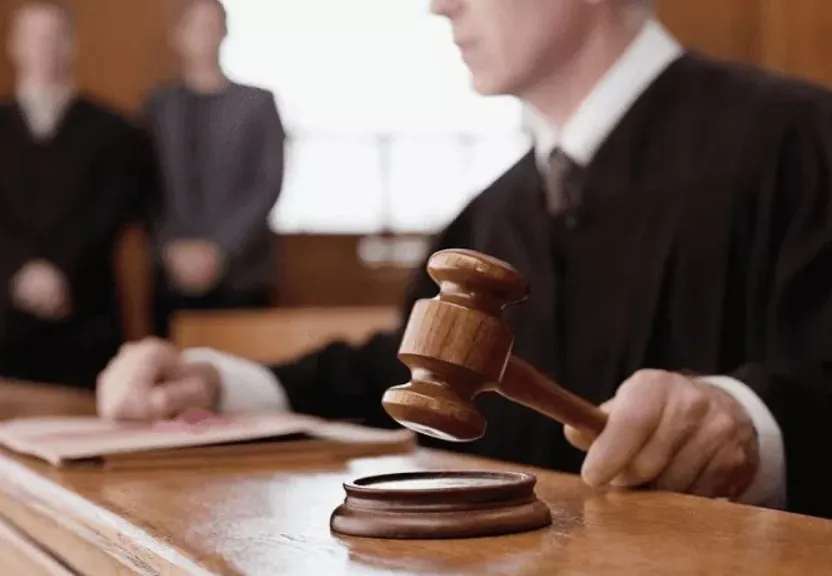 a judge sitting at a desk with a wooden gavel