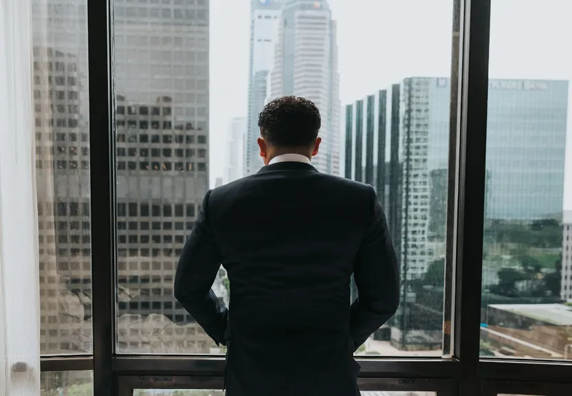 a man in a suit looking out of a window