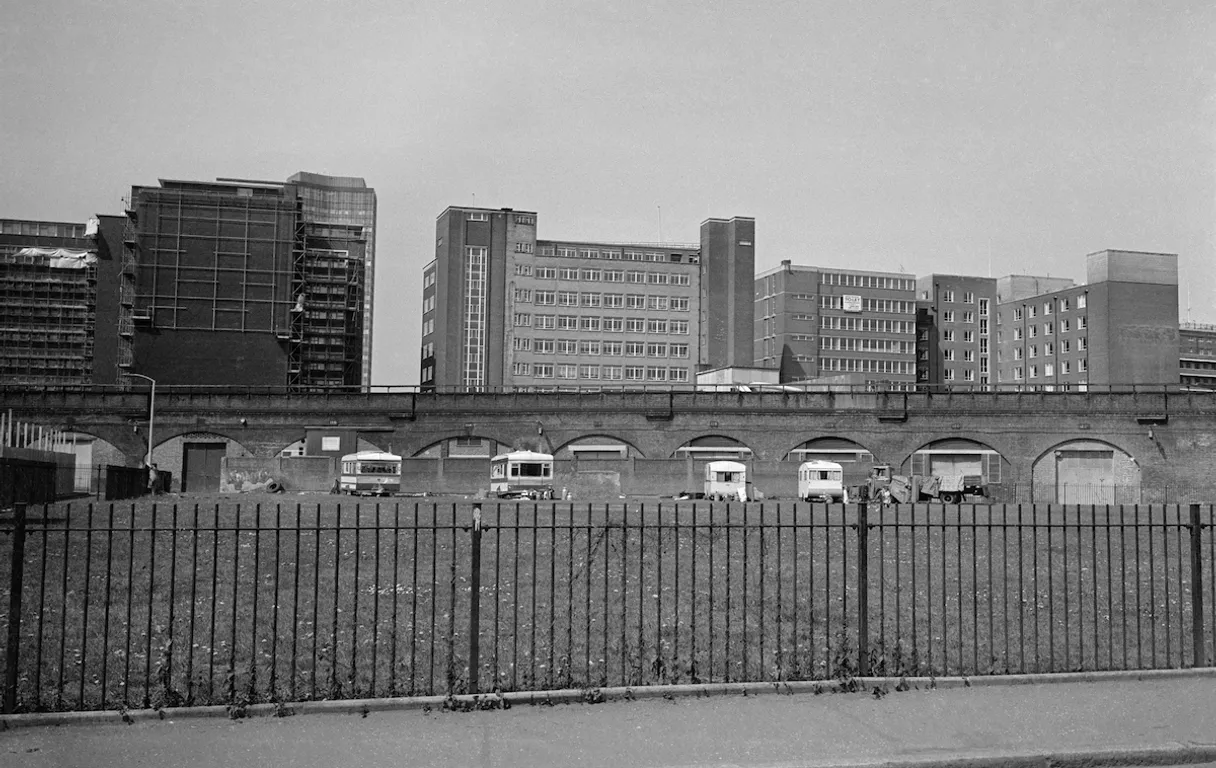 a black and white photo of a city with tall buildings birds flying in sky from left to right