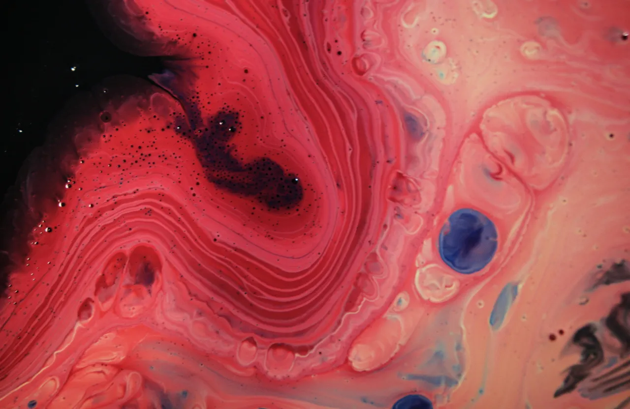 A flowing pink organism made of liquid paint on a wooden canvas