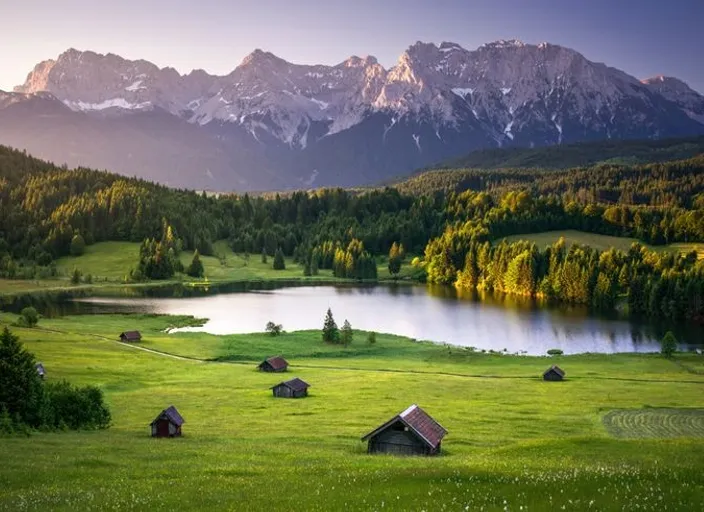 a grassy field with a lake and mountains in the background