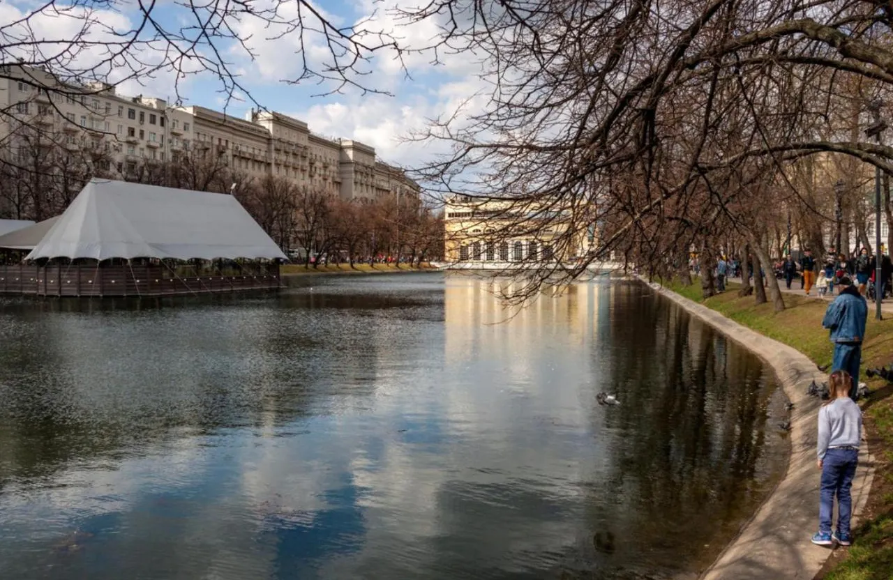 people are walking along the water in a park