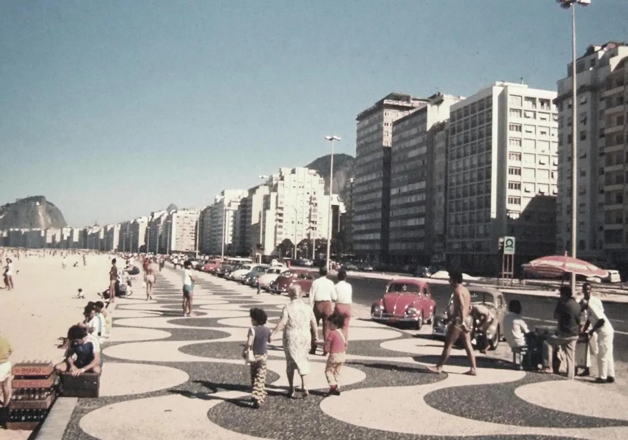 a group of people walking along a beach next to tall buildings