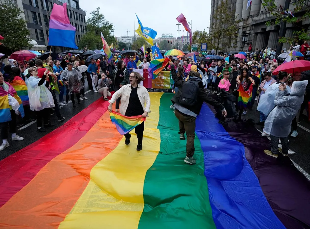 a man walking down a street holding a rainbow flag