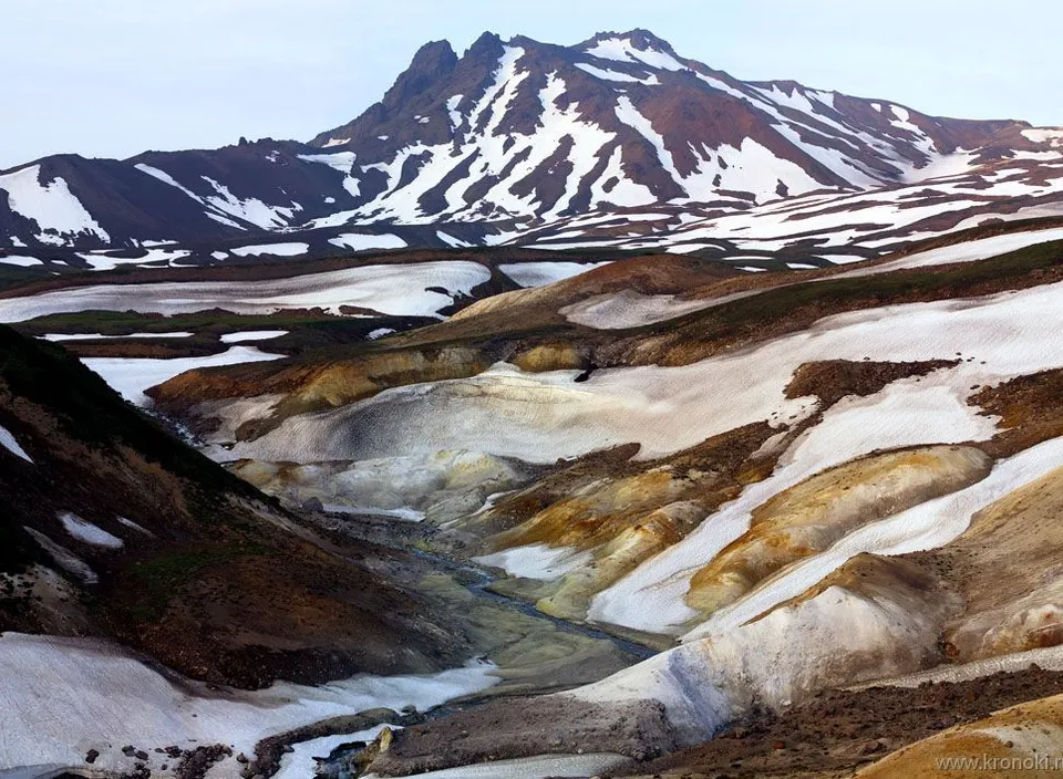 a mountain range covered in snow with a river running through it