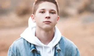 a young man in a blue jean jacket looking at the camera