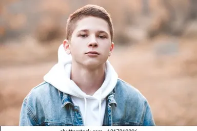 a young man in a denim jacket looking at the camera