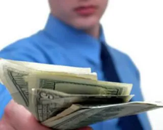 a man in a blue shirt is holding a stack of money