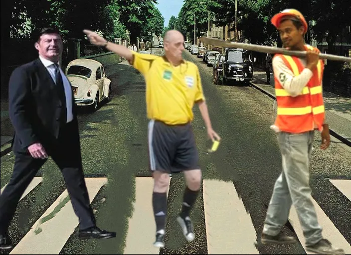 a man in a yellow shirt and a man in a black suit crossing a street