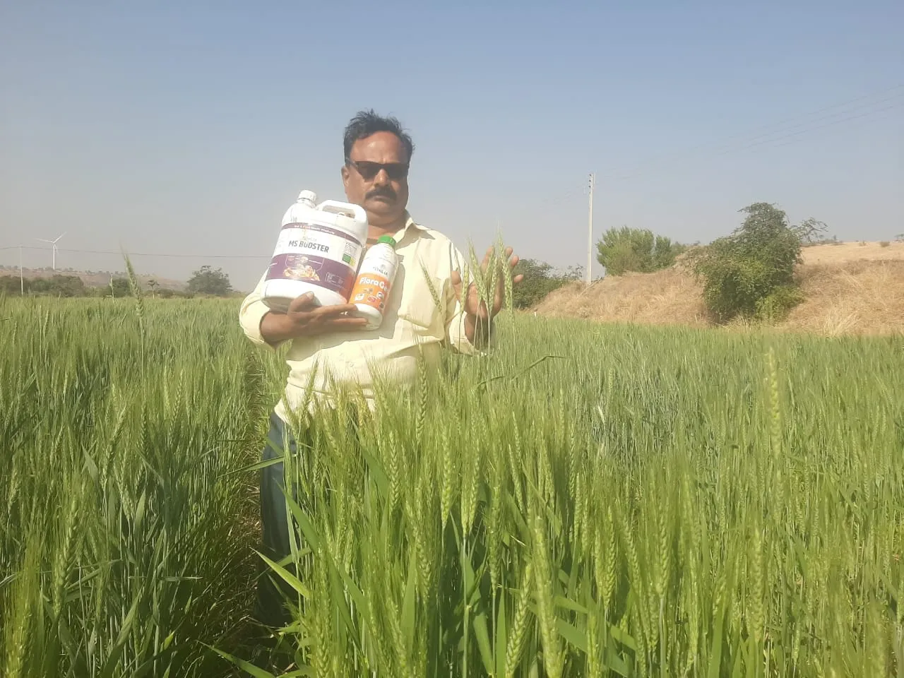 a man standing in a field holding a bottle of milk