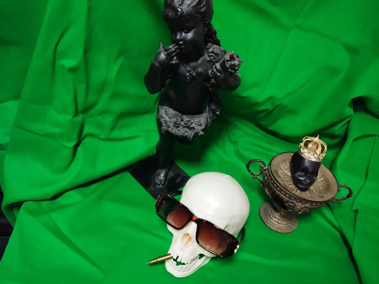 a pair of sunglasses and a fake plastic skull head on a green cloth
