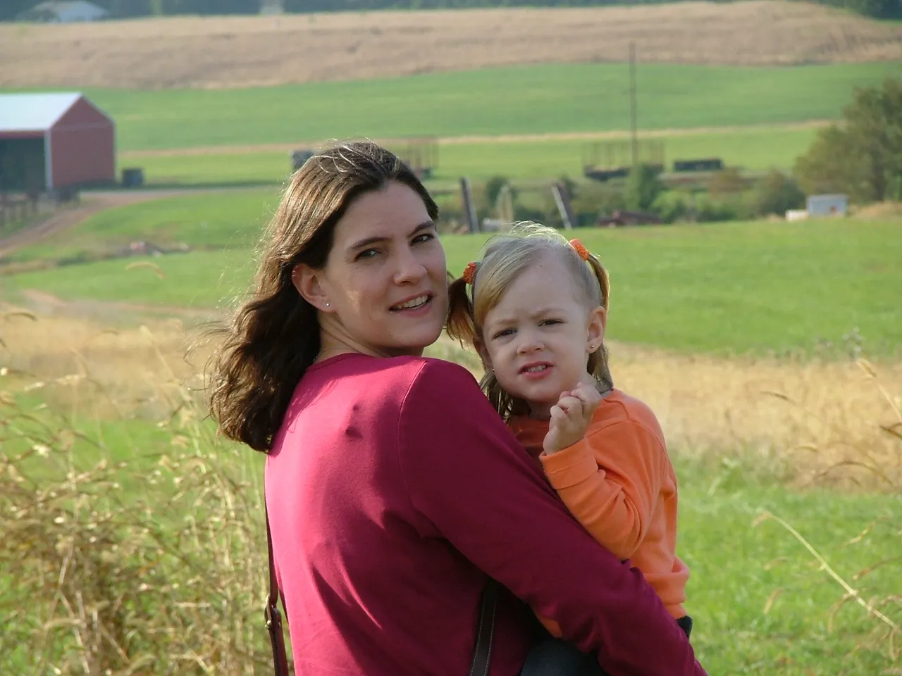 a woman holding a little girl in a field