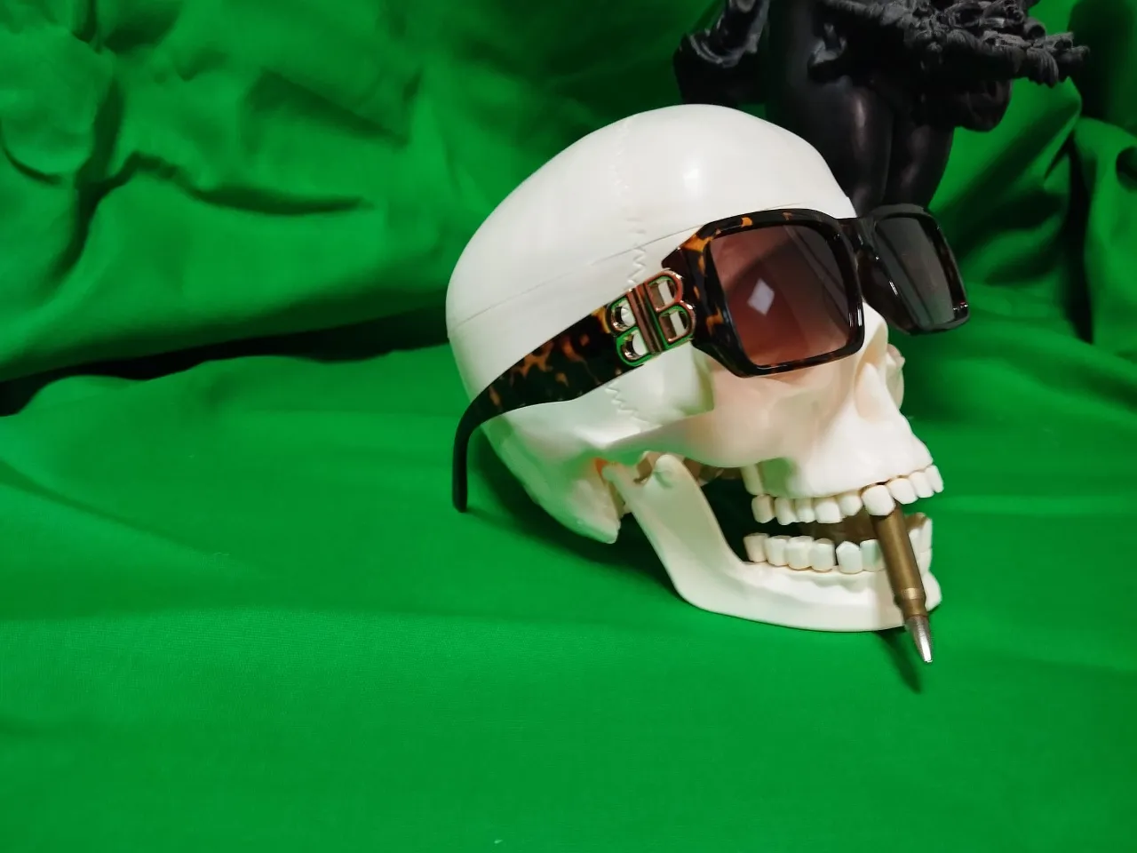 a white skull wearing sunglasses on a green background