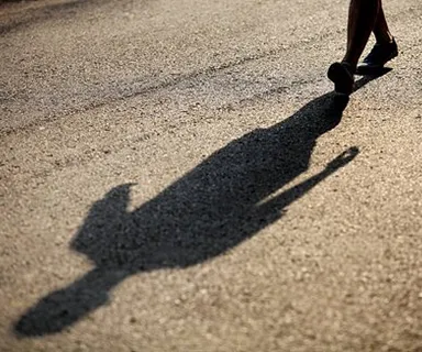 a shadow of a person walking down a street