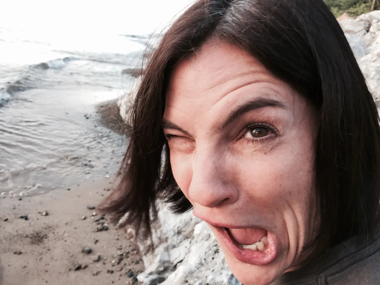 a woman sticking out her tongue on the beach