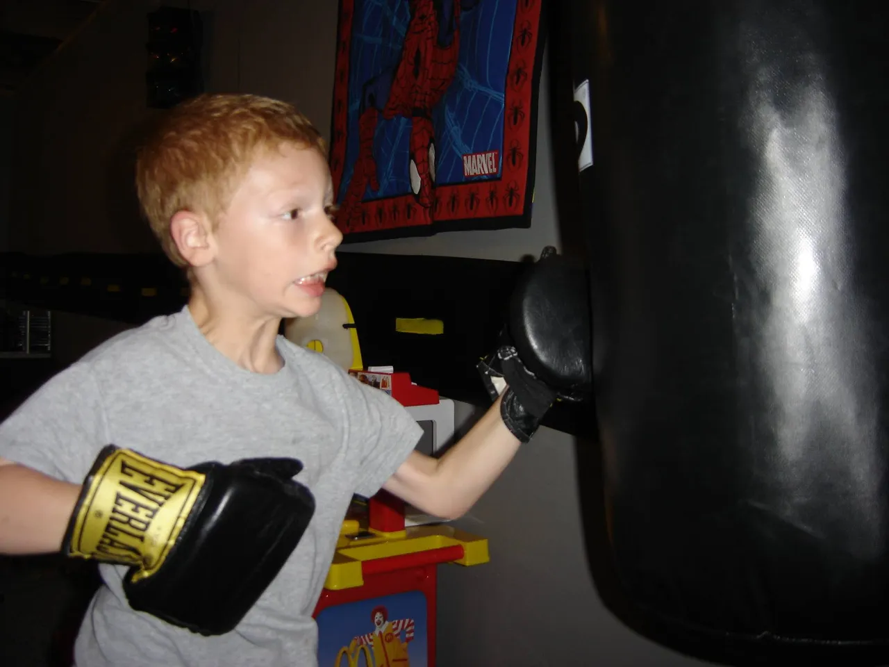 a young boy wearing a pair of boxing gloves and punching a heavy bag