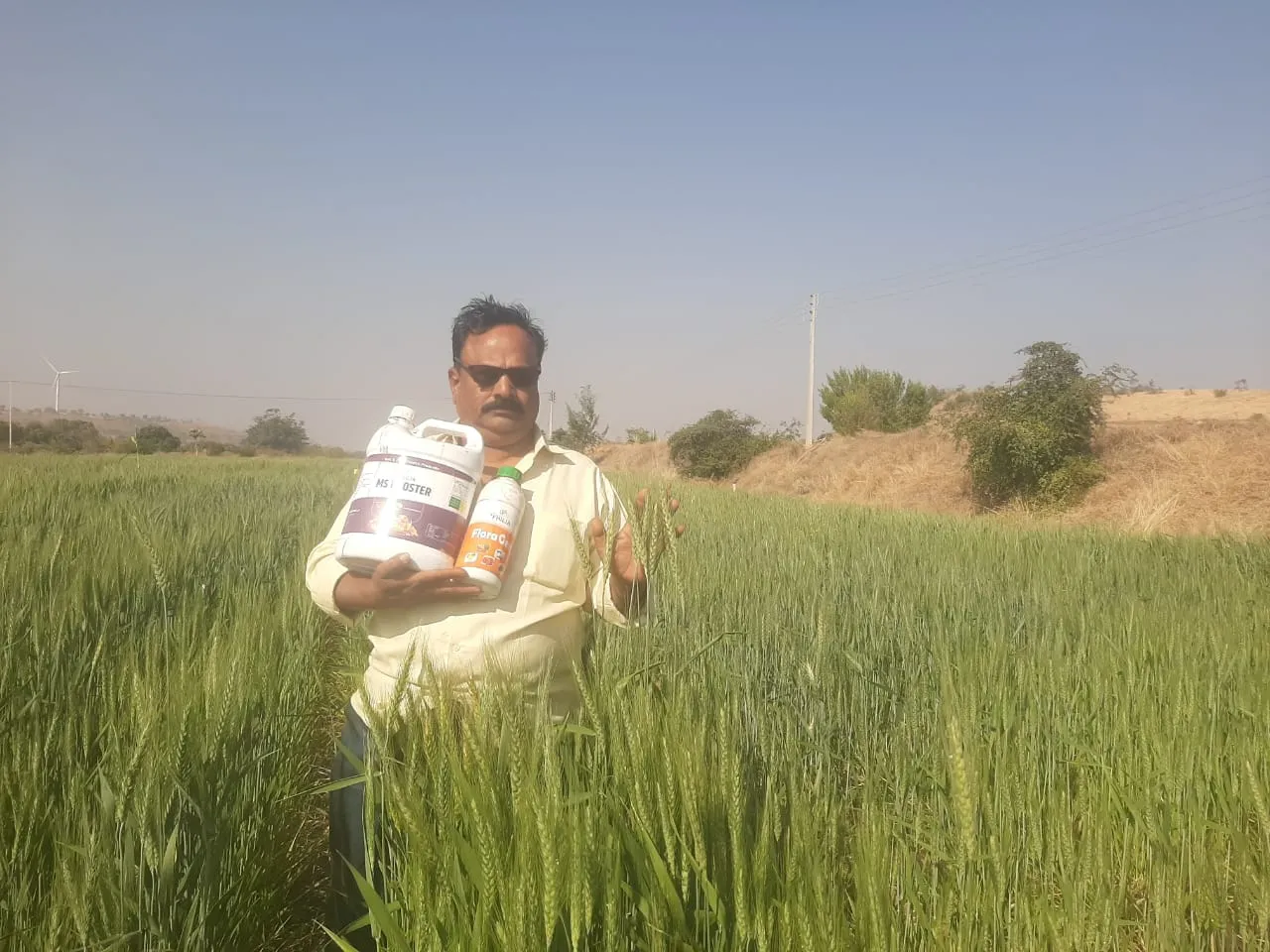 a man standing in a field holding two bottles of water