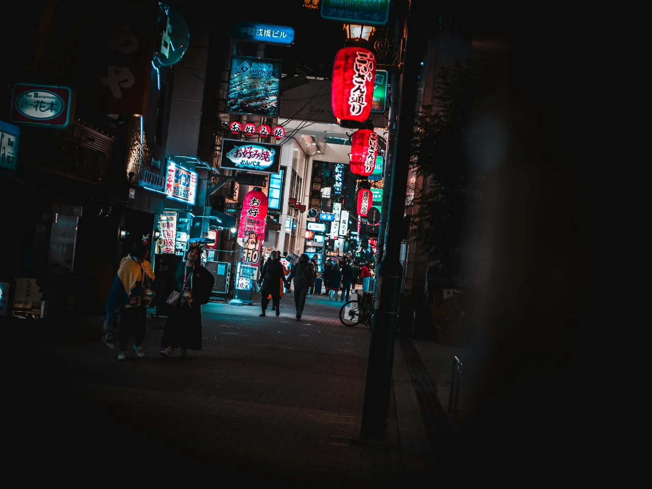 a group of people walking down a street at night  in Oasaka Japan