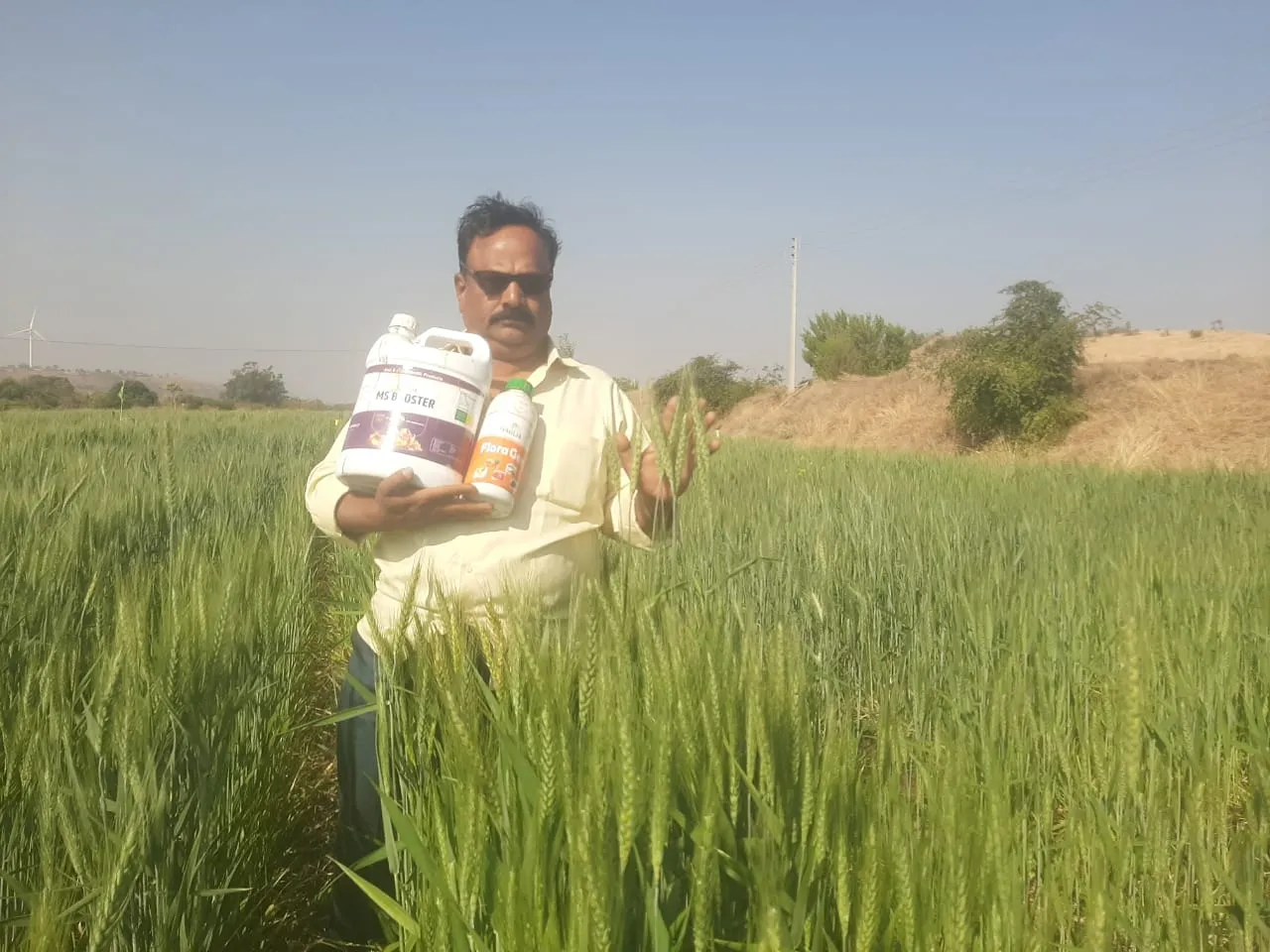 Pandu, a man standing in a field holding two bottles of water