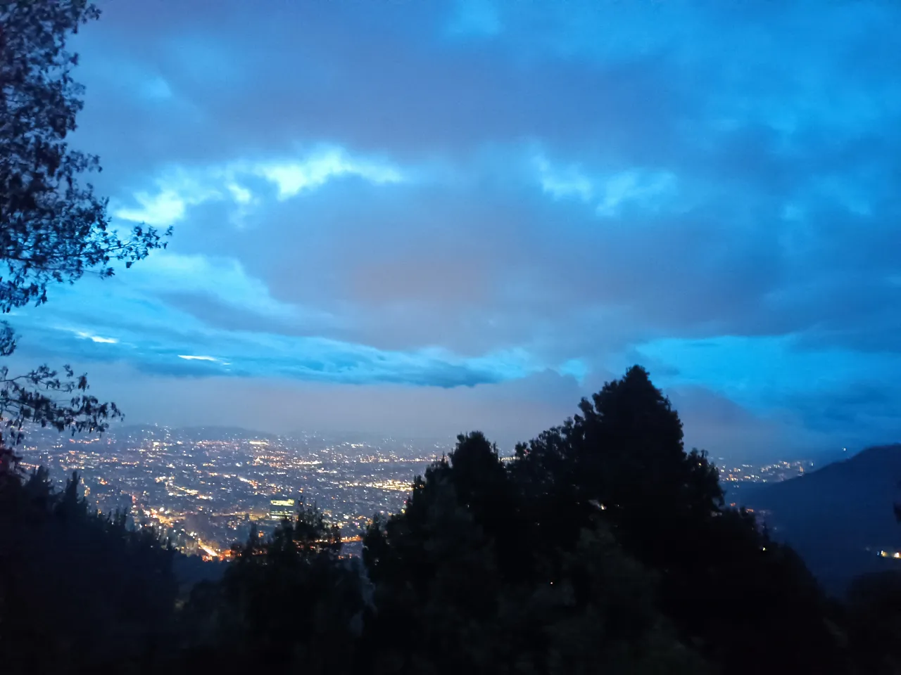 a view of a city at night from a hill