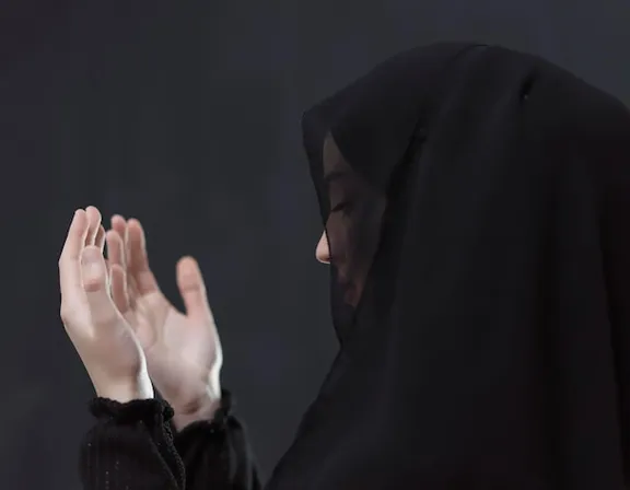 a woman in a black hijab is holding her hands together