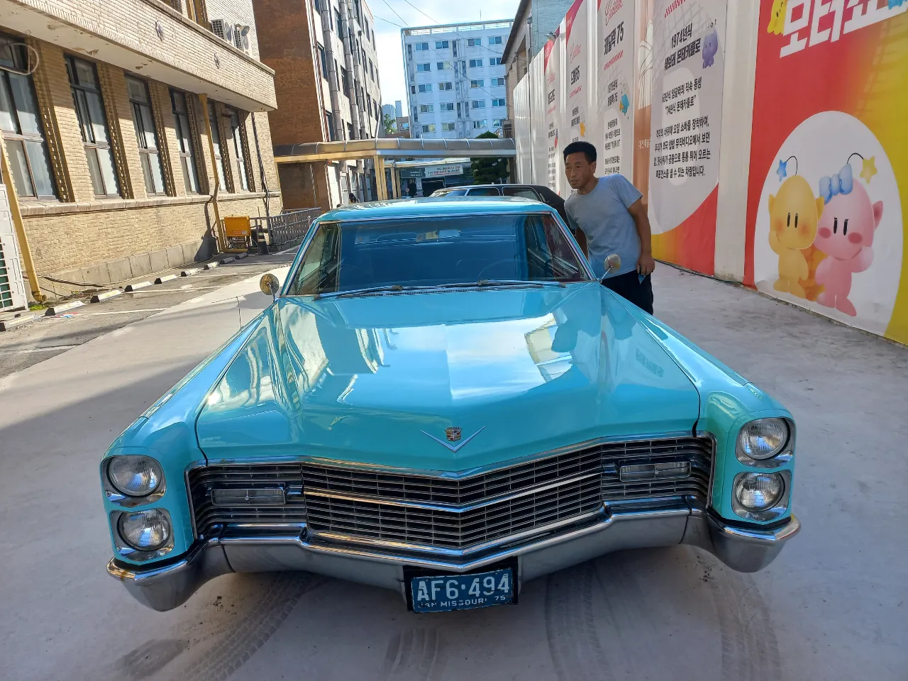 a man standing next to a blue car on a street