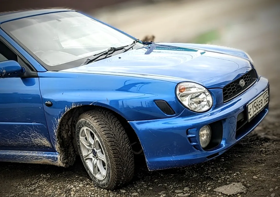 a blue car parking on the side of a road