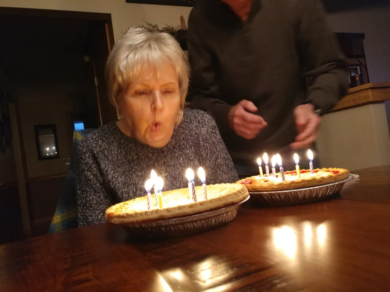 a woman blowing out candles and then smiling at camera