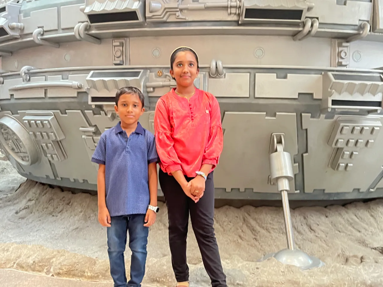 two children standing in front of a model of a battleship