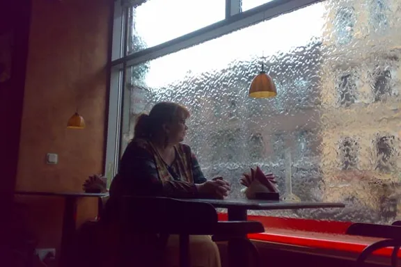 a woman sitting at a table in front of a window