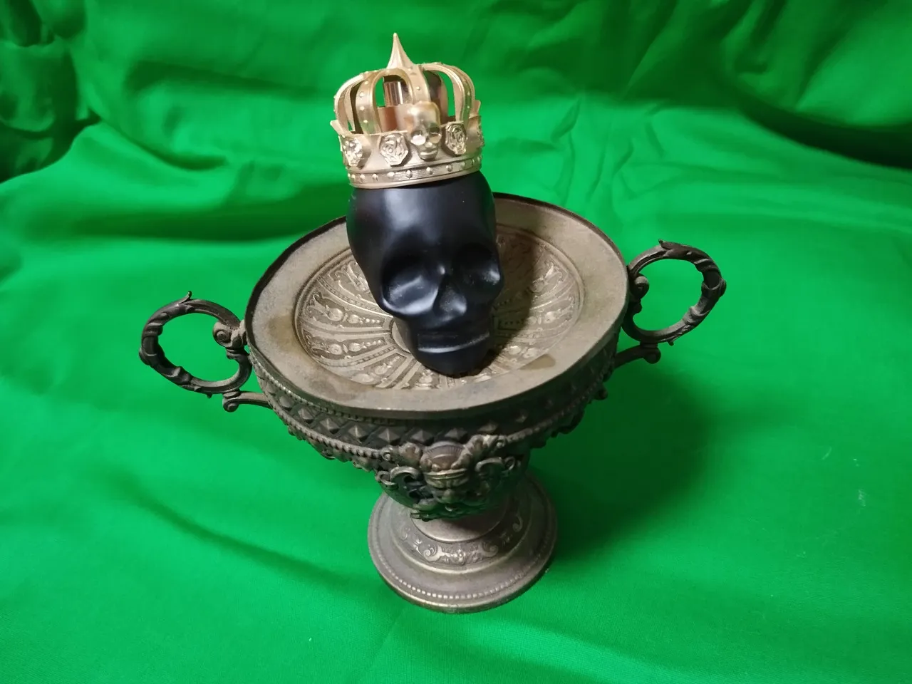 a metal vase with a crown on top of it