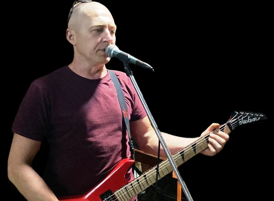 a man holding a guitar and singing into a microphone