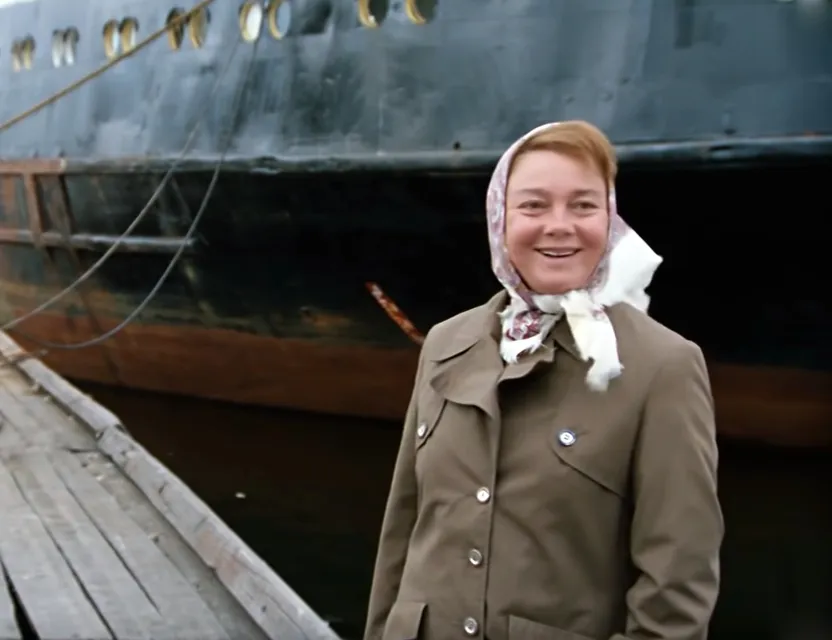 a woman standing on a dock next to a boat