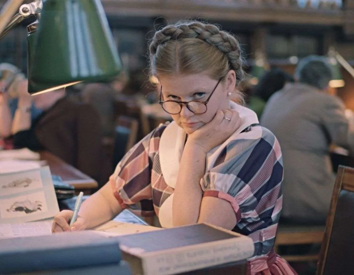 a woman sitting at a table with a book in front of her