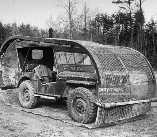 an old military vehicle is parked on a dirt road