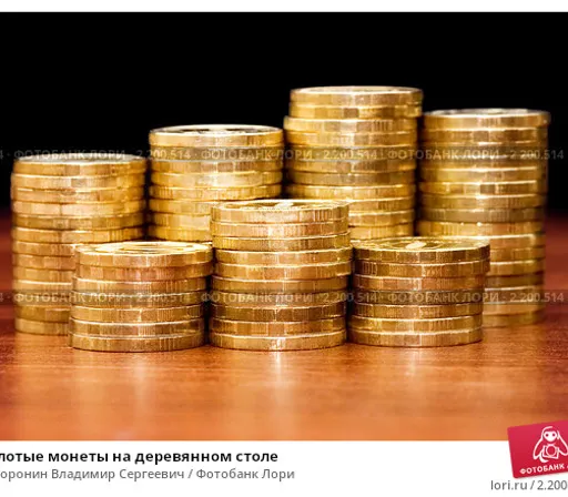 a pile of gold coins sitting on top of a wooden table