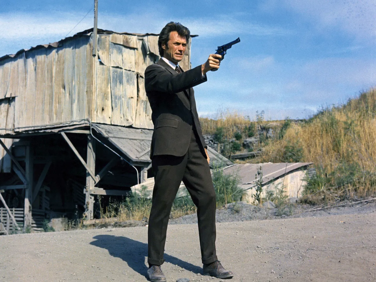 a man in a suit holding a gun while walking in san fransisco