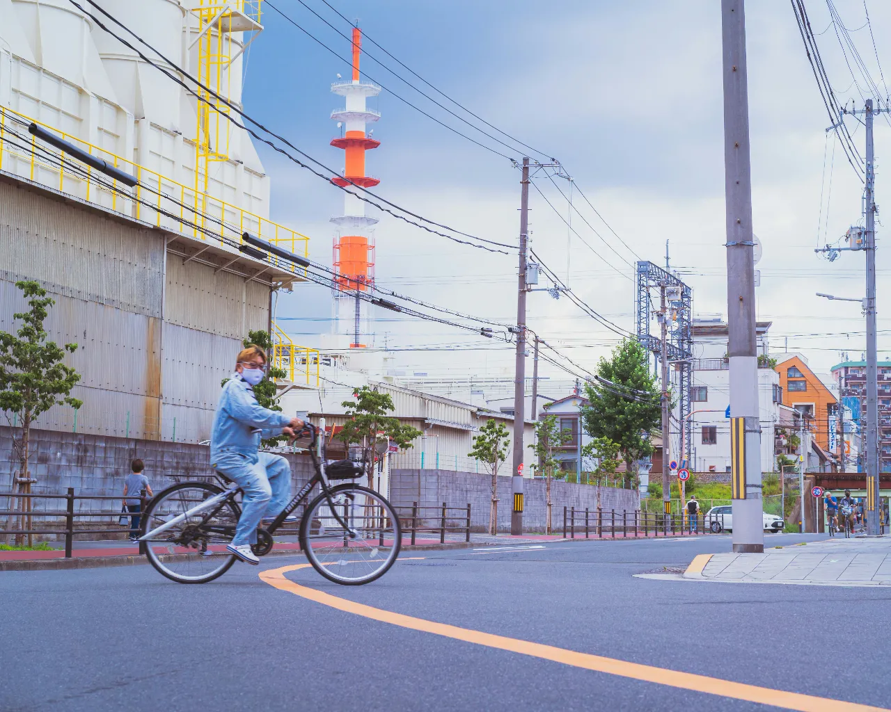 a man riding a bike down a street next to a tall building in Osaka Japan