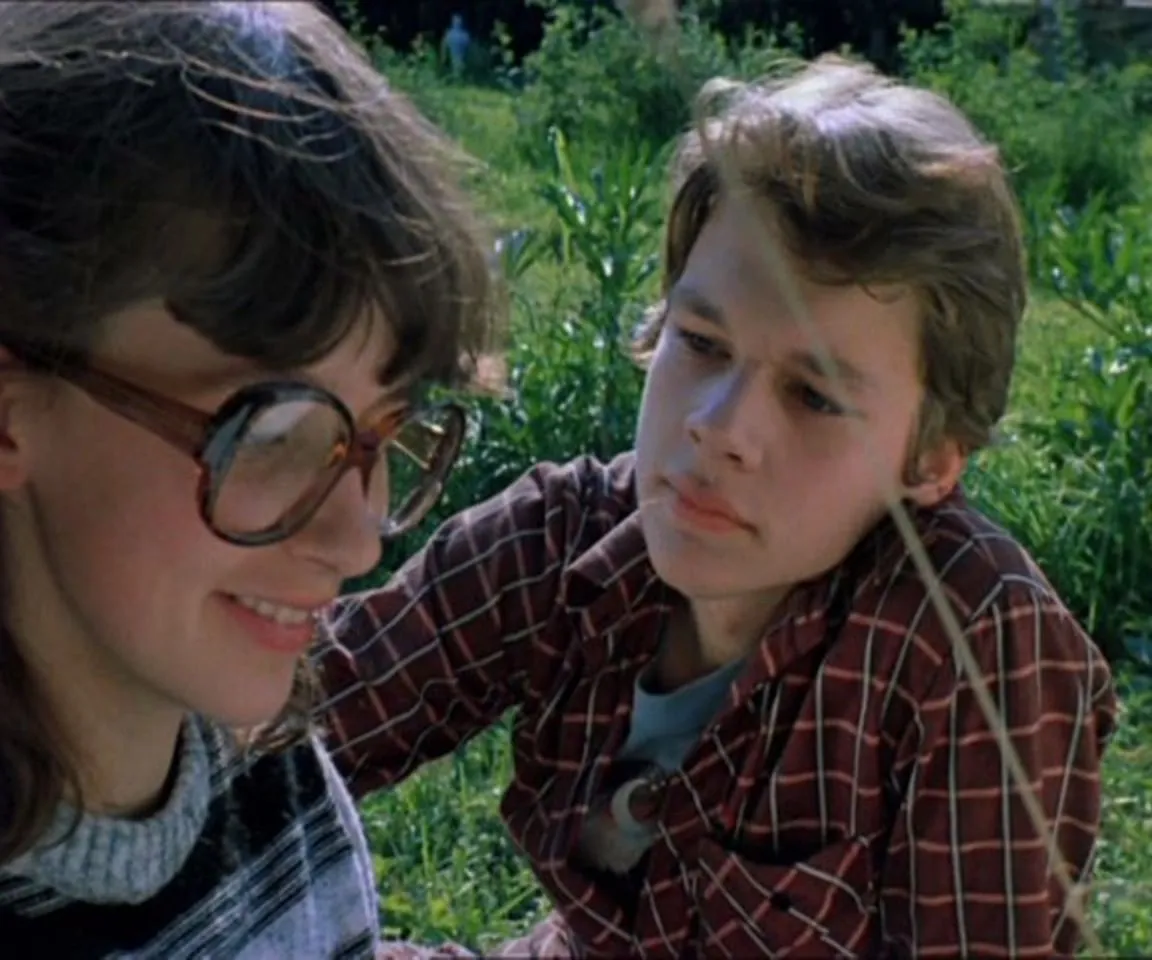 a young boy and a young girl sitting in the grass