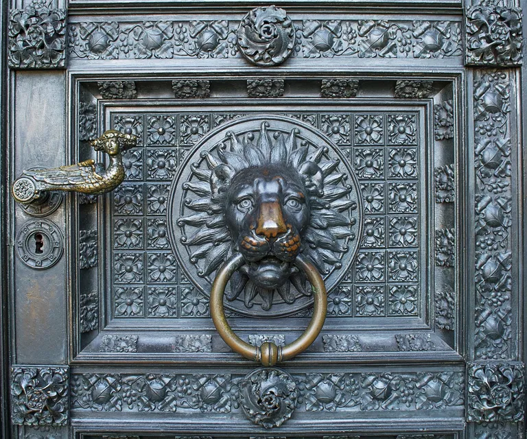 a metal door with a lion's head on it