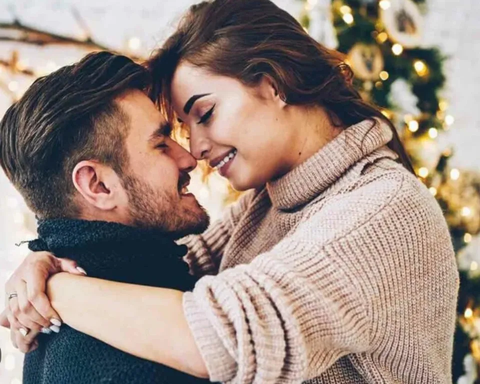 a man and a woman hugging in front of a christmas tree