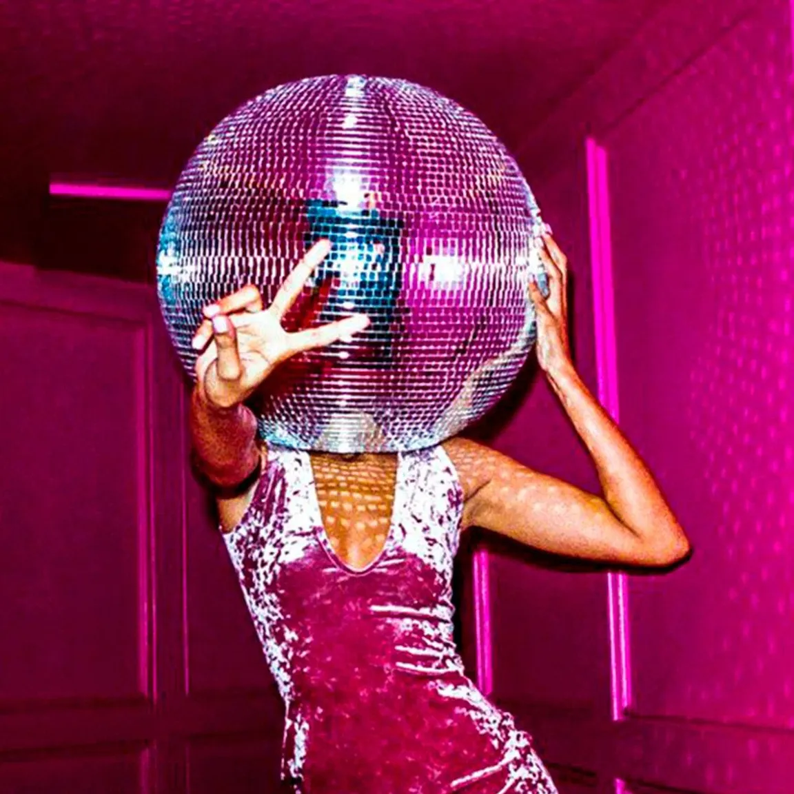 a woman in a pink dress holding a disco ball