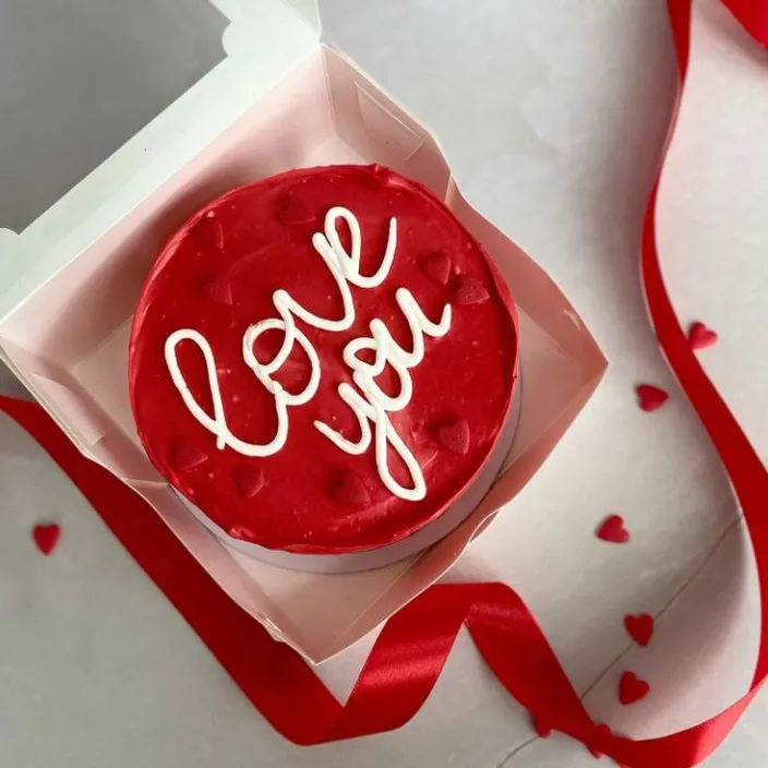 a red cupcake with white frosting in a box