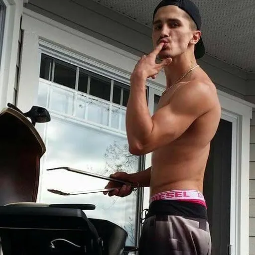 a shirtless man standing in front of a bbq