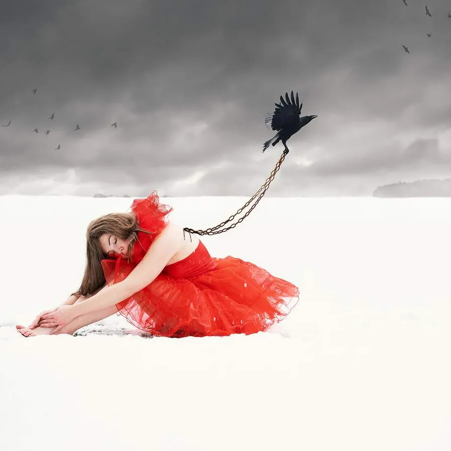 a woman in a red dress sitting in the snow