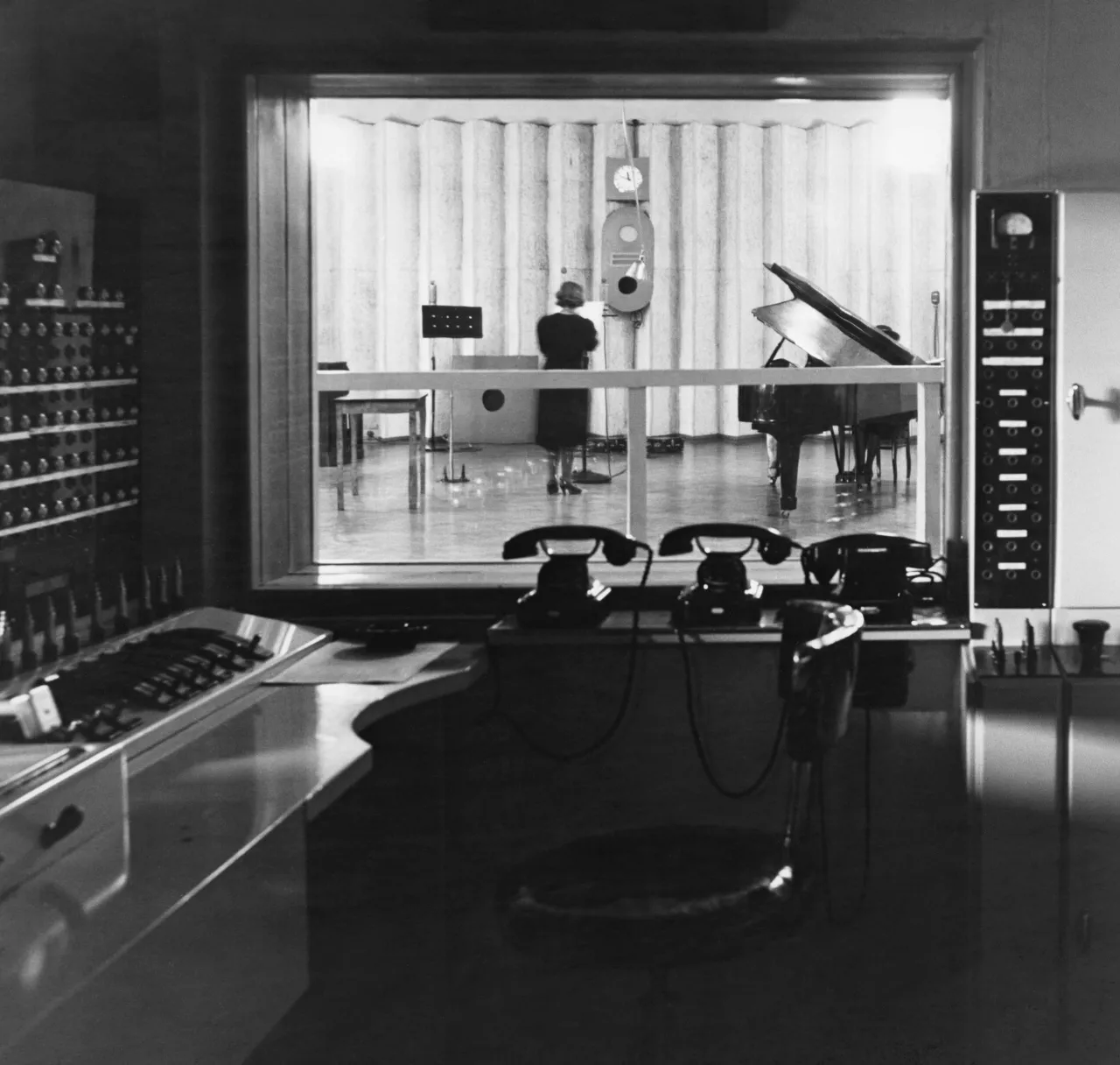 a black and white photo of a room for registration music with instrument and three old telephone