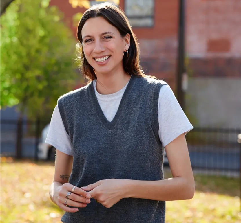 a woman standing in a park smiling at the camera