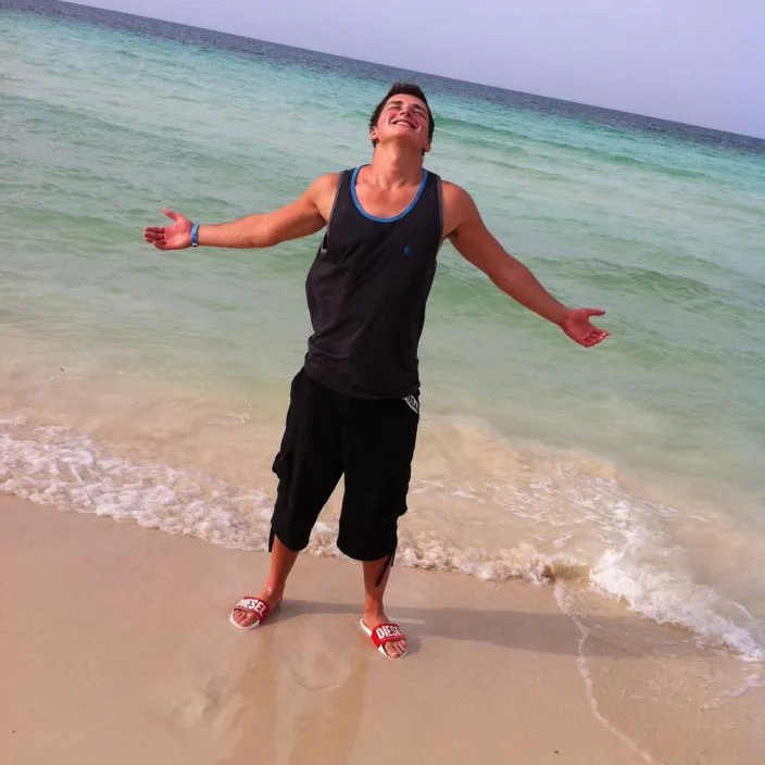 a man standing on top of a sandy beach next to the ocean