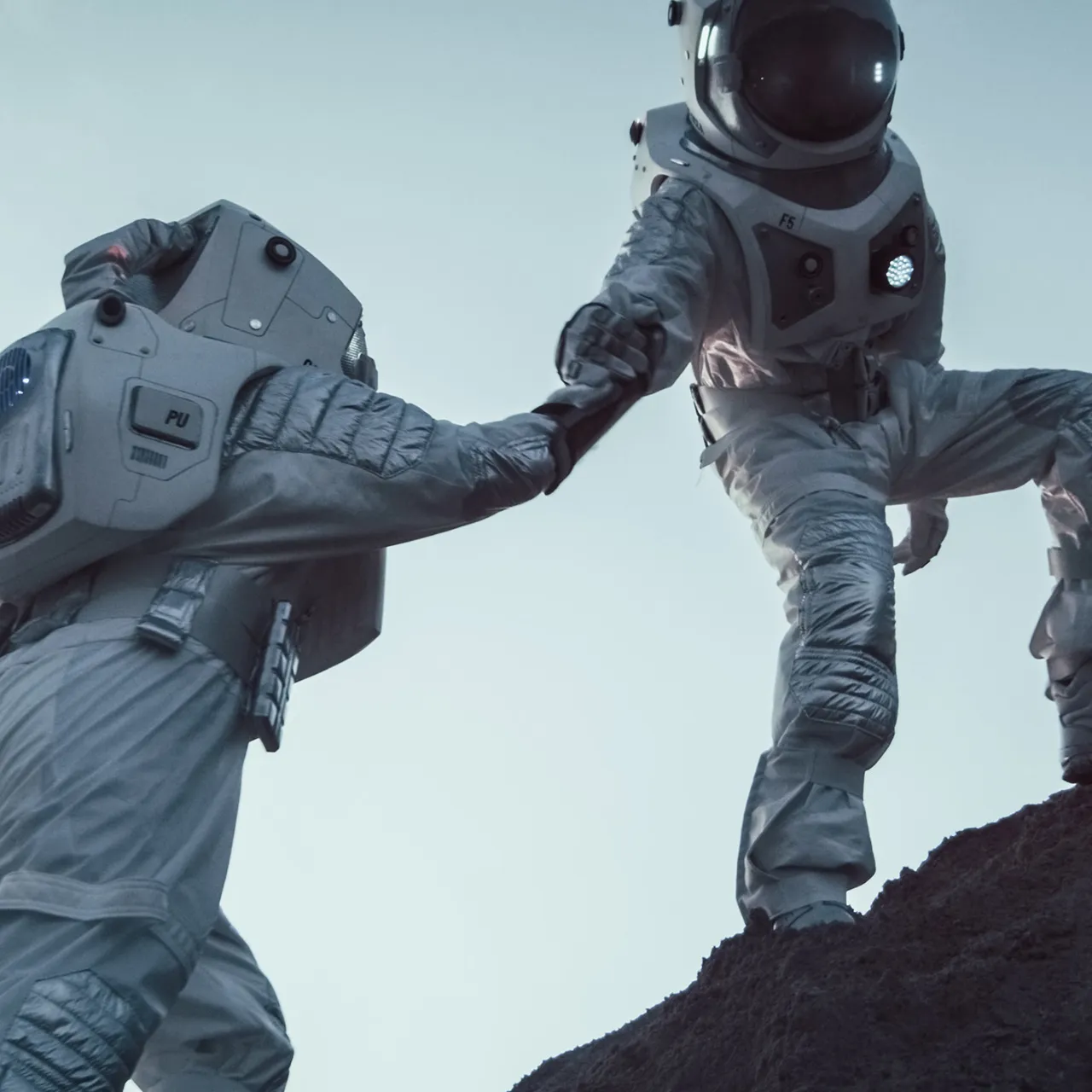 two men in spacesuits standing on top of a mountain